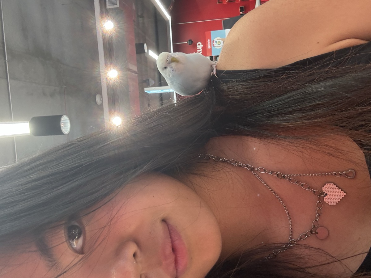 Arina Zhou with her budgie on her shoulder
